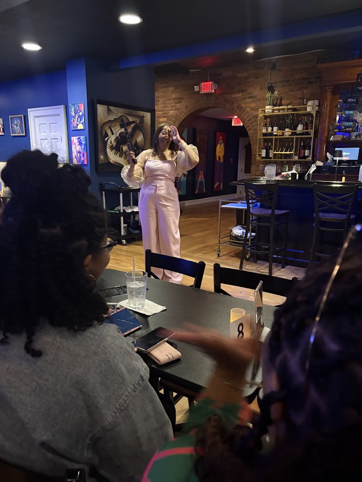 D.L. Augustine speaking with a microphone at an intimate venue